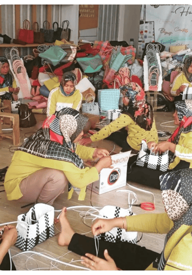 Artisans assembling handmade jali jali woven plastic bags together at Craftvitas Indonesia workshop.
