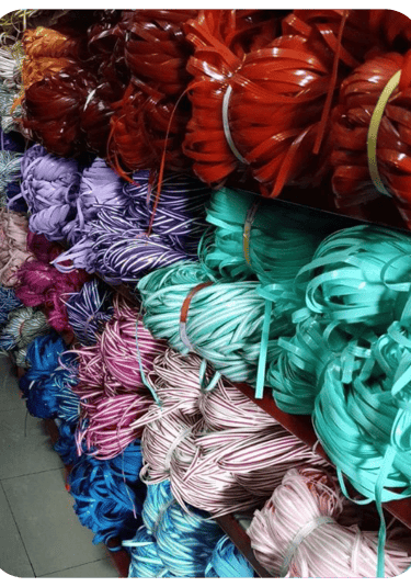 Bundles of multi colored recycled plastic weaving strips neatly stored and ready for handmade woven bag production.