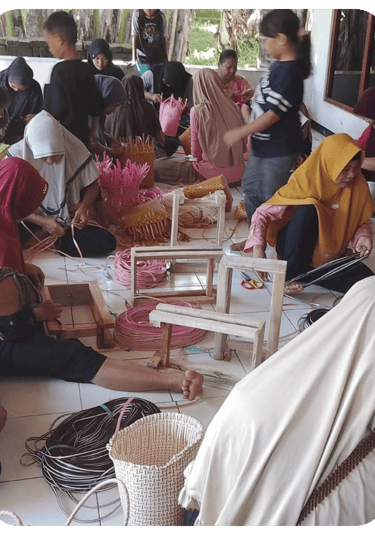 Artisans finishing colorful jali jali plastic woven bags by hand at Craftvitas Indonesia workshop.