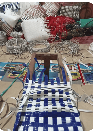 Shaping the base of a yellow and white handmade woven bag using recycled plastic weaving strips at Craftvitas Indonesia.