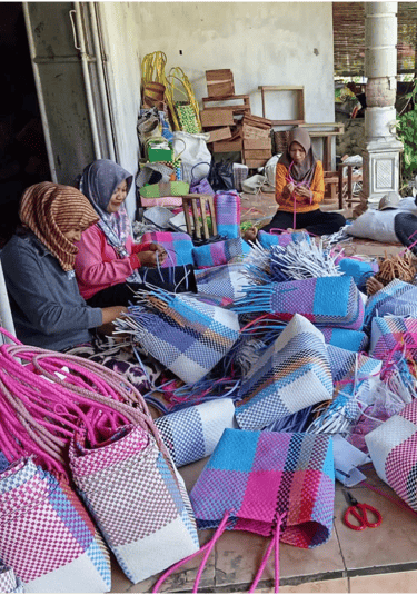 Artisans shaping and adjusting handmade plastic woven bags during production at Craftvitas Indonesia.