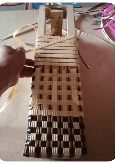 Ongoing weaving process of a blue and white handmade plastic woven bag at Craftvitas Indonesia workshop.