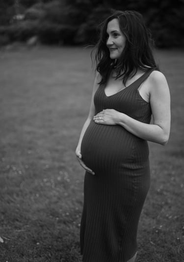 black and white image of pregnant woman holding her baby