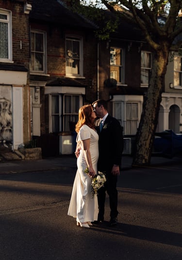 bride and groom standing on the street and kissing during the golden hour