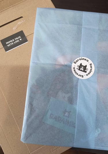 Handmade item wrapped in blue tissue paper with a Rarainka cat logo sticker.