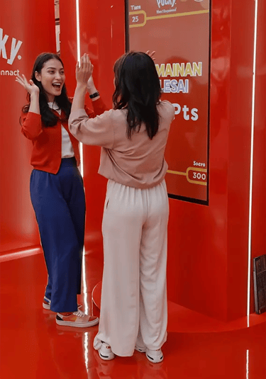 Two female participants high-fiving and laughing after playing at Pocky booth