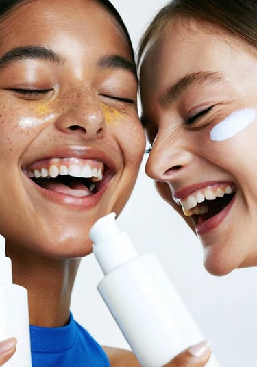 two girls laughing holding bottles of skincare