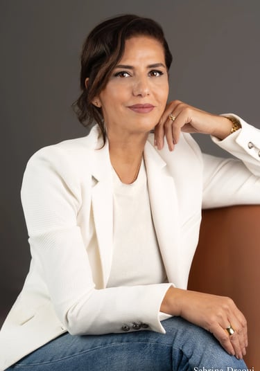 a corporate woman in a white jacket and jeans sitting on a chair