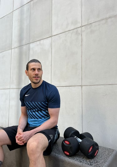 A personal trainer sat with dumbbells at his side