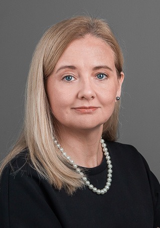 Maritas Zitmanes portrets. Viņa ar gaišiem, plecu garuma matiem, tumšā apģērbā 
