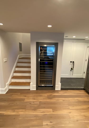 The remodeled basement featuring a built-in wine cooler, hardwood floors and dark kitchen cabinetry.