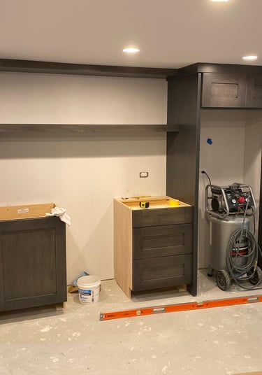 Basement remodel in progress featuring dark gray custom cabinetry and built-in shelving.