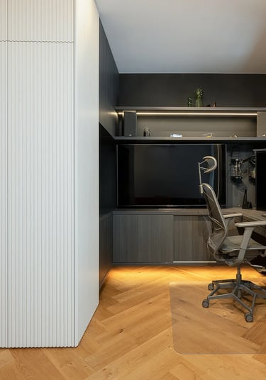 Nowoczesne biuro domowe z biurkiem, monitorami, krzesłem i zabudową ścienną.