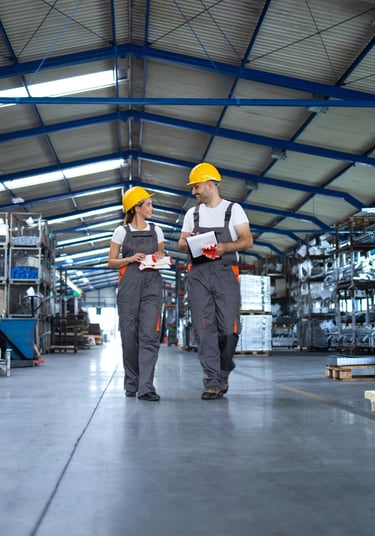 Dos trabajadores en un almacén con una gran cantidad de equipos.