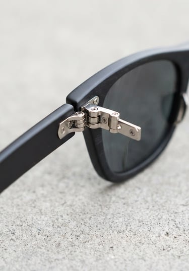 Sharp high-key product photography of premium polarized sunglasses, highlighting metallic frame hinges and clean structural details on a neutral concrete backdrop, 50mm lens.