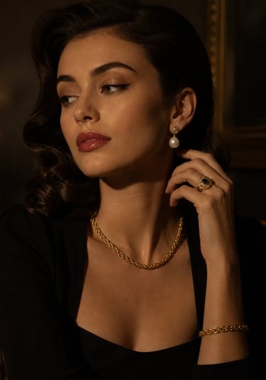 Elegant woman wearing vintage-style gold jewelry, pearl earrings, and a black dress in a dim setting.