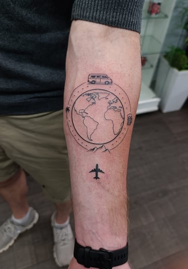 Man's arm tattoo of a plane flying over a globe.  Tattooed at Katarsis Studio in Lima