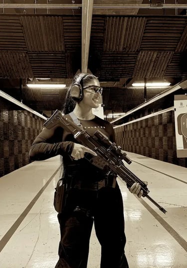 mais alhajri smiling while holding a rifle at an indoor shooting range
