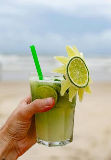 a person holding a drink in a glass, Caipirinha, In Copacabana Beach, Rio de Janiero, Brazil