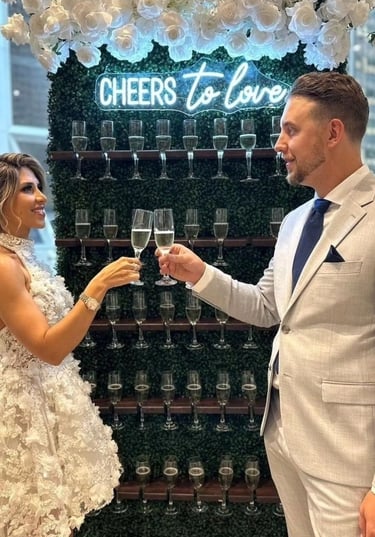 a man and woman holding champagne flutes in front of a sign that says cheers to love