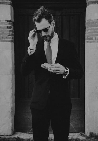 a man in a suit and sunglasses is holding a glasses case.