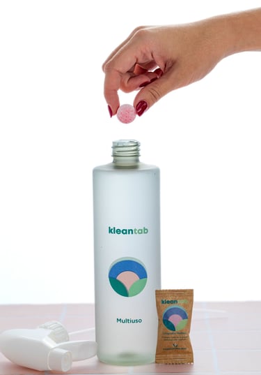 Tableta efervescente de limpieza siendo introducida en una botella reutilizable con agua, mostrando el proceso de preparación