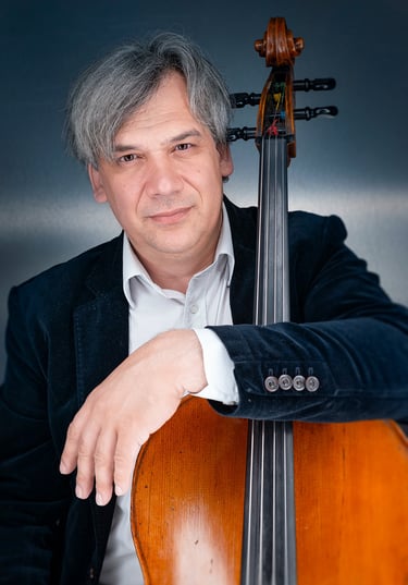 a man in a suit and tie is holding a cello