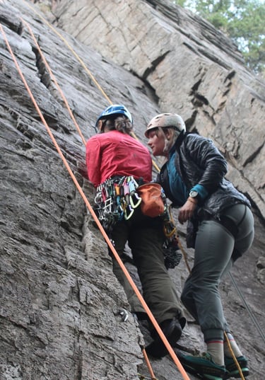 Two people in conversation while climbing a rock face outdoors