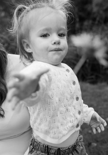 Black and white portrait of a girl reaching out for a flower