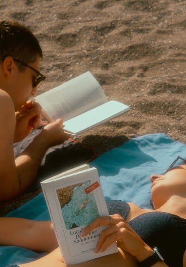 a man and woman reading a book on a blanket