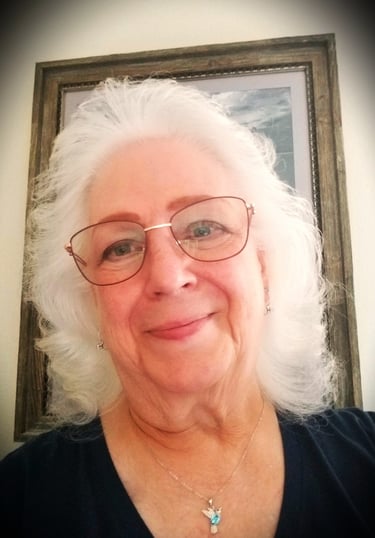 a lady with glasses and a bird necklace on.