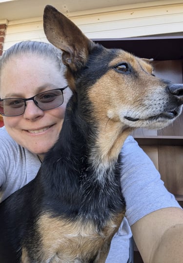 Laura Hooton on the left, in a grey tshirt, smiling, with a brown and black dog on the right.