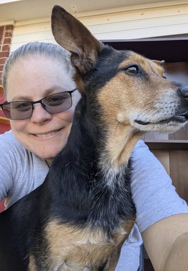 Laura Hooton on the left, in a grey tshirt, smiling, with a brown and black dog on the right.
