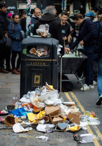 person standing beside garbage bin