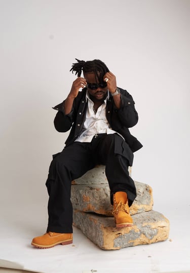 a man in a suit and sunglasses sitting on a rock
