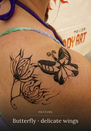 A delicate black butterfly and floral henna tattoo design applied to a woman's shoulder.