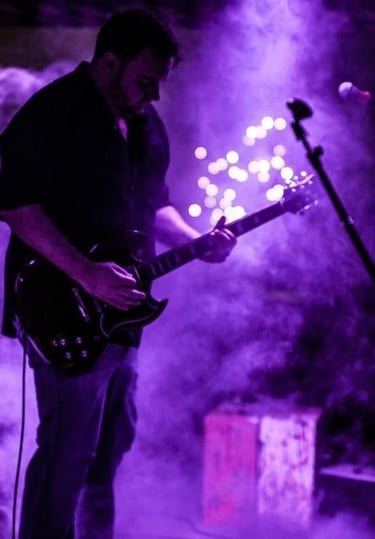 John playing guitar with purple smokey background