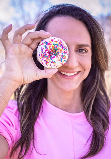 a woman holding a doughnut in front of her face