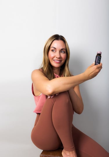 a woman sitting on a wooden table with a bottle of life vantage liquid collagen