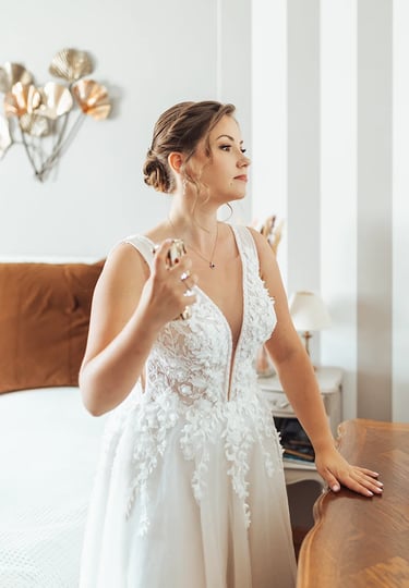 Mariée dans une belle robe qui se parfume durant ses préparatifs.