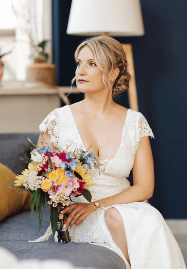 Mariée pensive tenant son bouquet coloré avant la cérémonie.