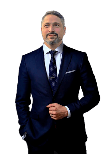 Homem branco de barba grisalha sorrindo vestindo terno e com gravata azul marinho