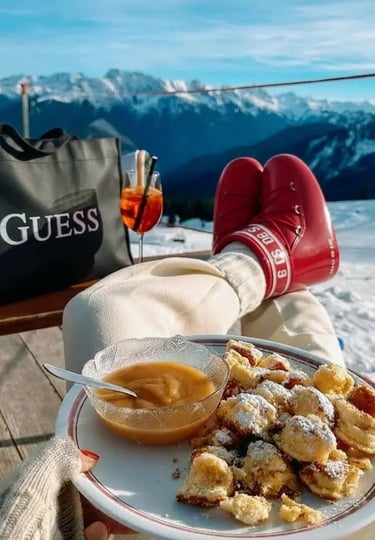 A long charcuterie spread arranged on a pair of skis in the snow, featuring cheeses, nuts, and dried