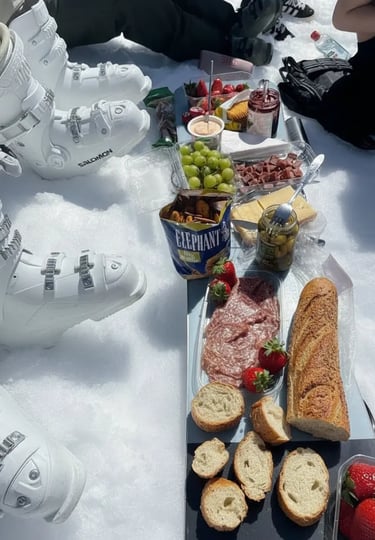 Aesthetic winter scene of a wooden tray with pastries and a mug of coffee on the snow, with a scenic