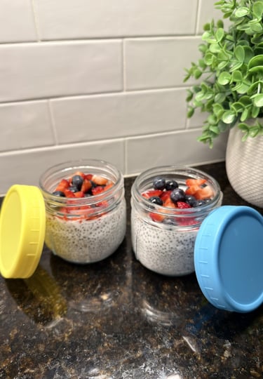 Two glass jars of chia seed pudding topped with berries on a kitchen counter for weekly meal prep