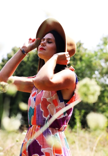 photo jeune femme en robe fleurie avec un chapeau au milieu d'un champs