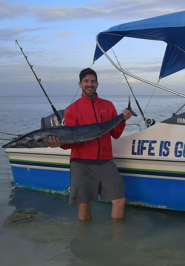 Tourist with a local fisherman in Zanzibar proudly displaying their fresh catch after a fishing trip on the Indian Ocean