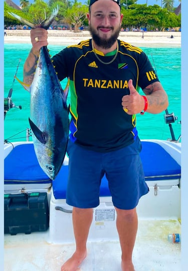 Happy tourist in Zanzibar proudly holding a big tropical fish after an exciting fishing trip on the Indian Ocean