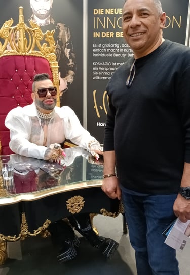 Fashion designer Harald Glööckler posing in a gold throne next to a fan at a beauty event.