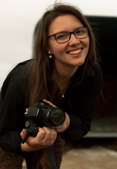 woman in glasses smiling and holding a camera